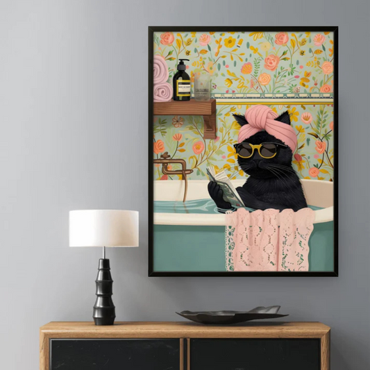 Framed artwork of a black cat in a bath with floral decorations on a wall above a wooden cabinet.