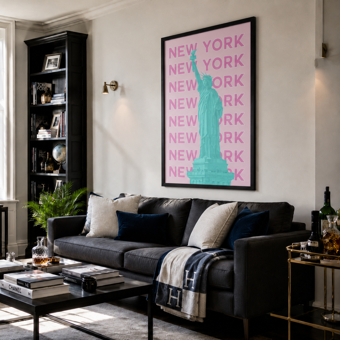 A modern living room featuring a large framed art print on the wall. The print has a pink background with the word 'NEW YORK' repeated vertically in light pink and a turquoise Statue of Liberty silhouette.