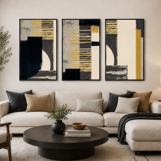 A modern living room featuring a three-piece abstract wall art set with black, gray, white, and yellow geometric patterns, hung above a beige sectional sofa.