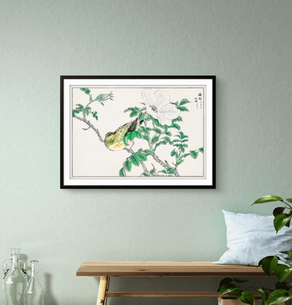 Framed artwork of birds on branches with green leaves on a light gray wall.