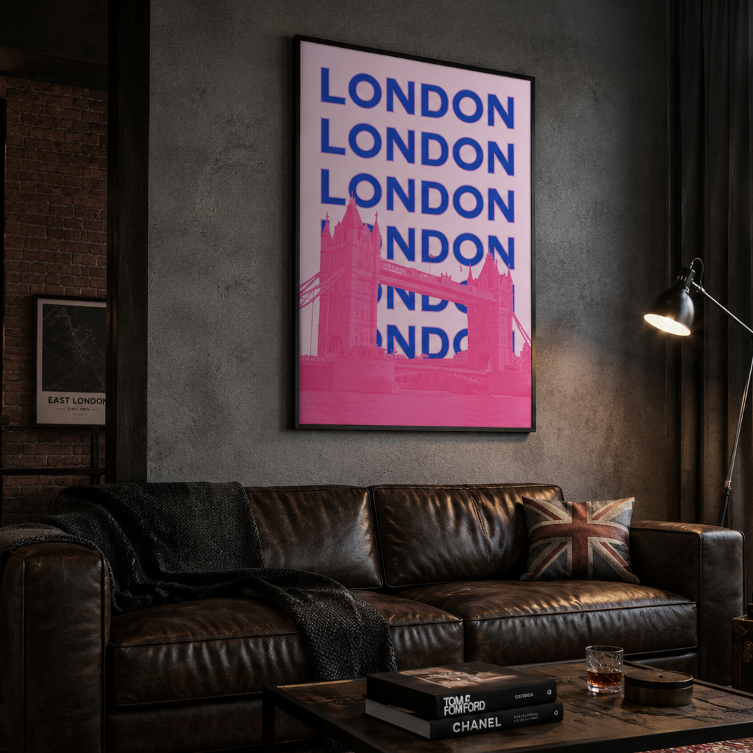 A framed London city art print with bold blue text and a pink bridge silhouette hanging on a dark gray wall above a brown leather sofa in a moody, stylishly decorated room.