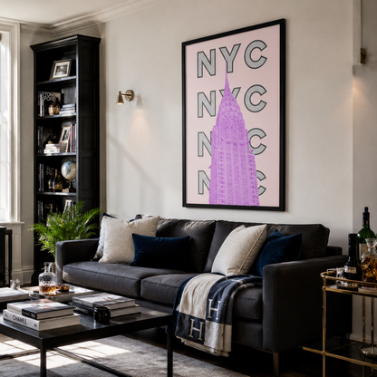 A framed vertical wall art print featuring a pink and purple New York City skyline with stacked 'NYC' text, displayed in a modern living room above a dark gray sofa.