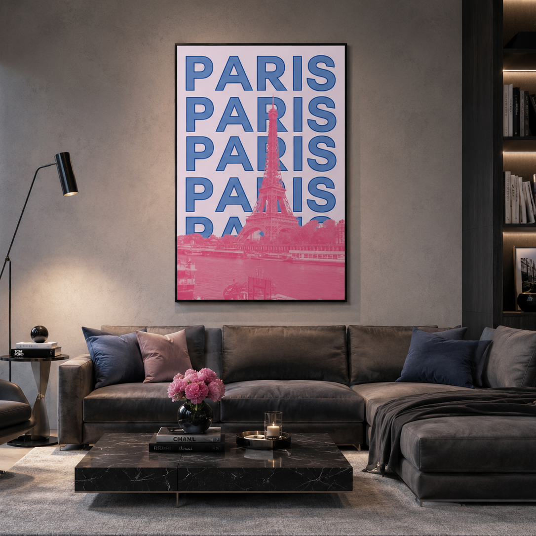 A framed vertical wall art print featuring the word 'PARIS' repeated in blue with a pink Eiffel Tower silhouette and pink lower section, displayed above a dark gray sectional sofa in a modern living room.