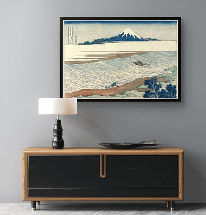 Framed artwork of a mountain landscape above a wooden cabinet with a lamp and decorative plate.