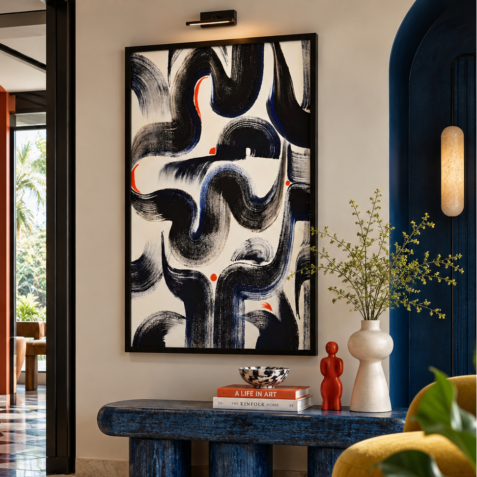 A large framed abstract wall art print with sweeping black, navy, and white brushstrokes and small orange-red accents, displayed in a styled interior hallway above a blue bench.