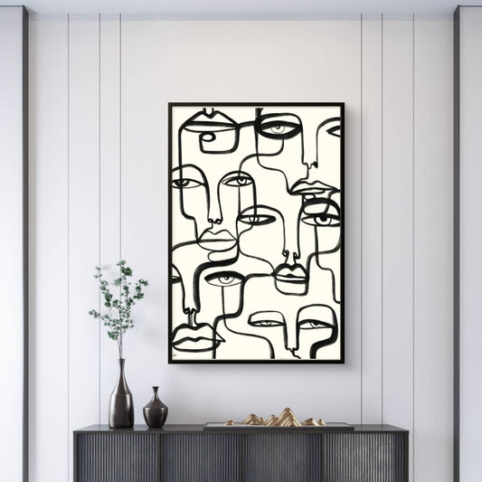 Abstract art piece of faces on a wall above a dark piece of furniture.