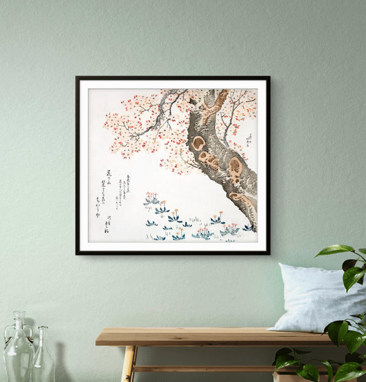 Framed artwork of a tree with flowers on a light green wall above a wooden bench.