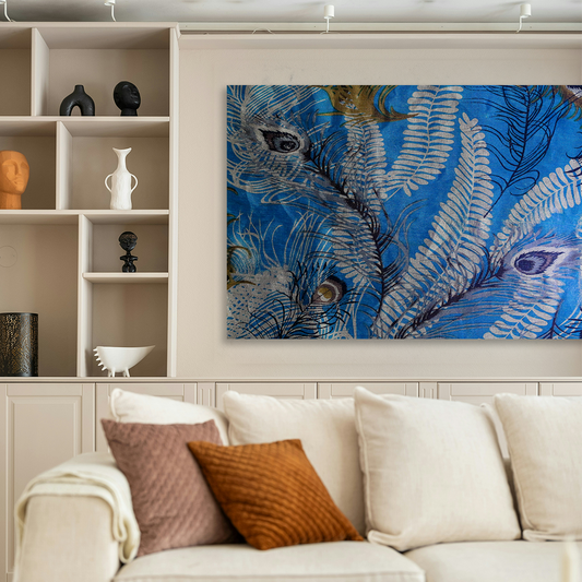 A large rectangular wall art piece featuring blue and white peacock feather artwork, displayed above a cream-colored sofa in a modern living room setting.