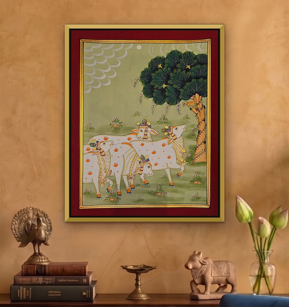 Gaumata Grazing Under the Kadamb - Sage Pichwai styled on a wall in a gold metal frame (frame sold separately)